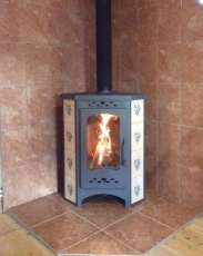 Недорогая печь-камин Бавария угловая с плитой незабудка Амазонка бай фото в интерьере в Минске